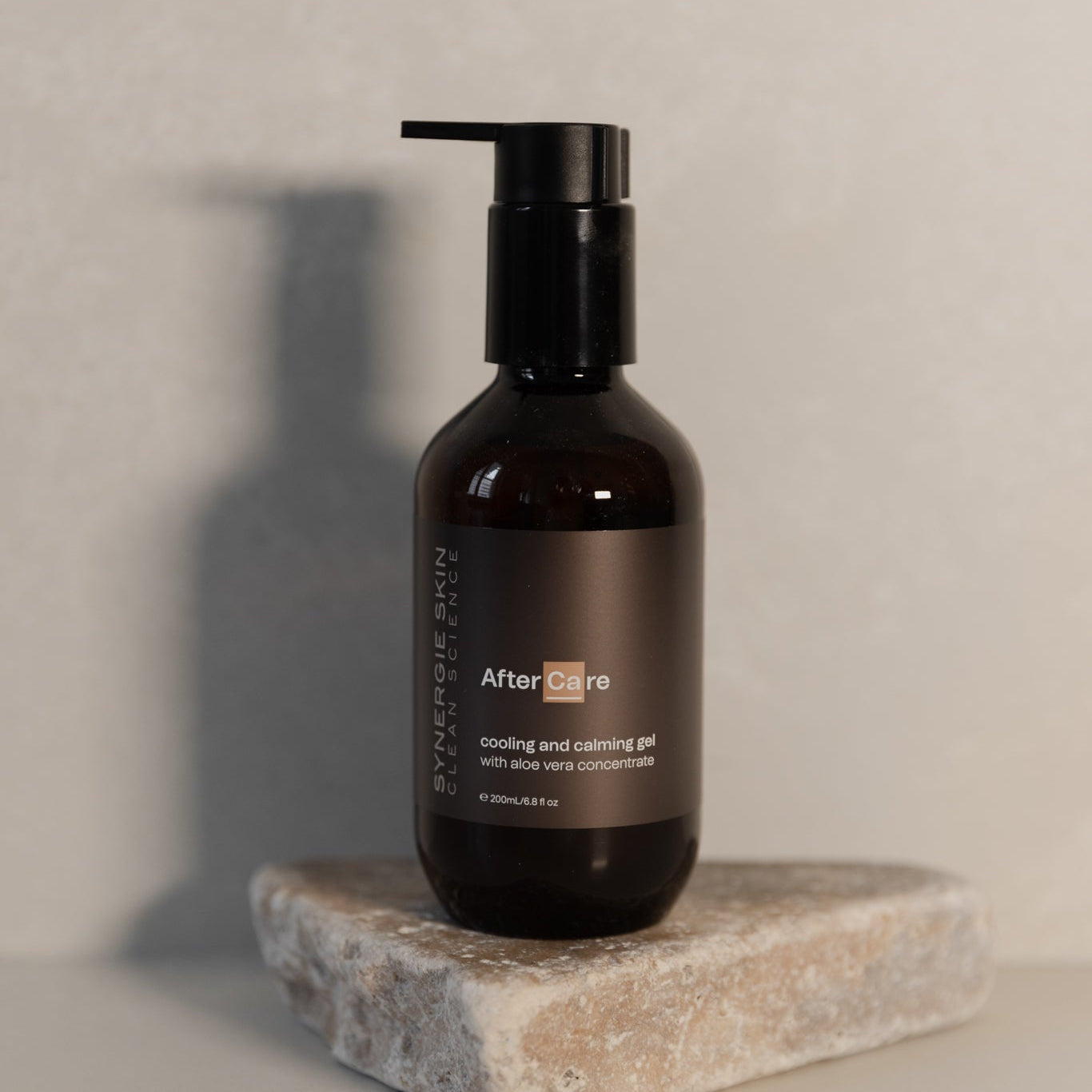 Black bottle labeled 'After Care' on a stone surface with a neutral background