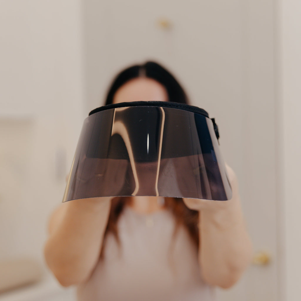 Person holding a black and gold lampshade in front of their face