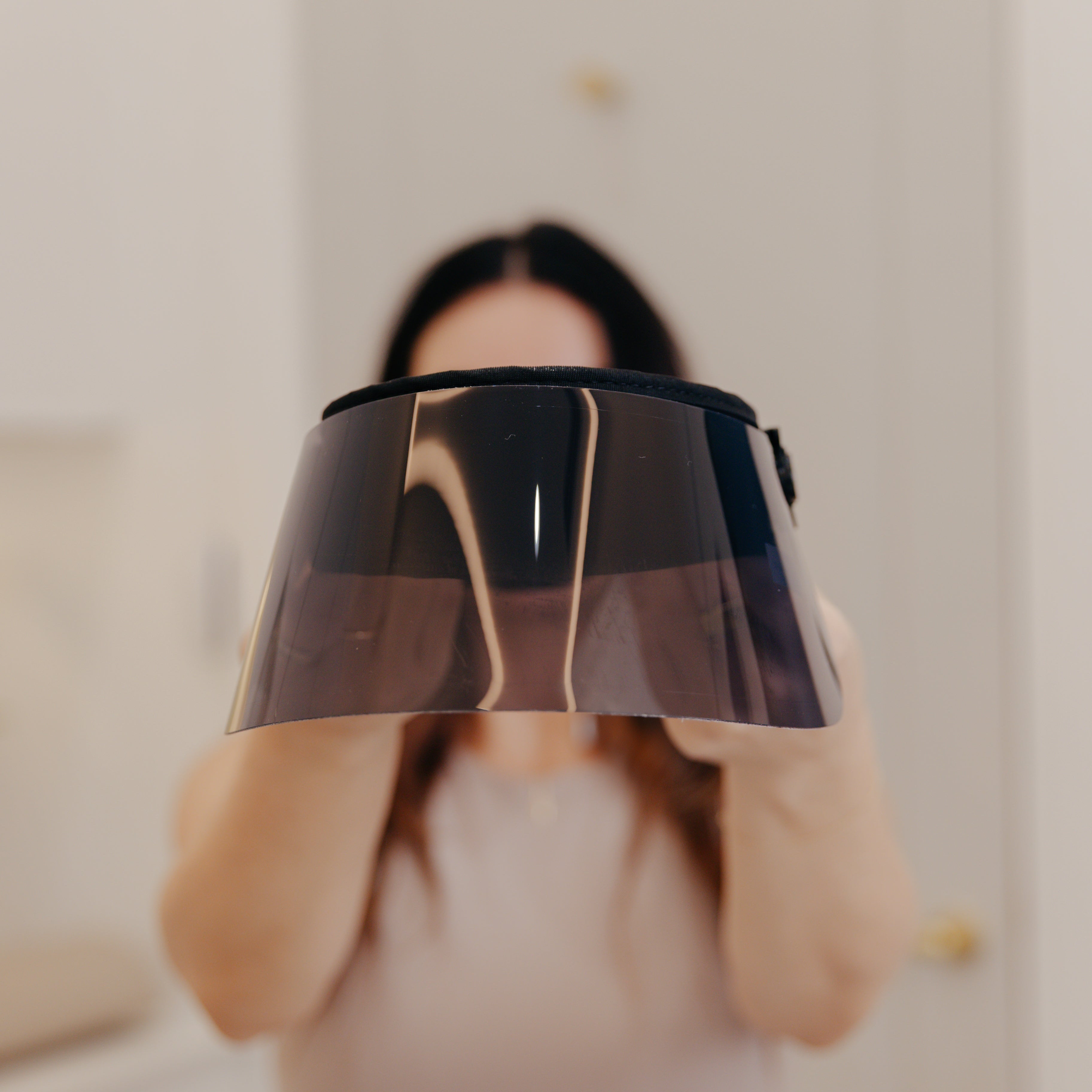 Person holding a black and gold lampshade in front of their face